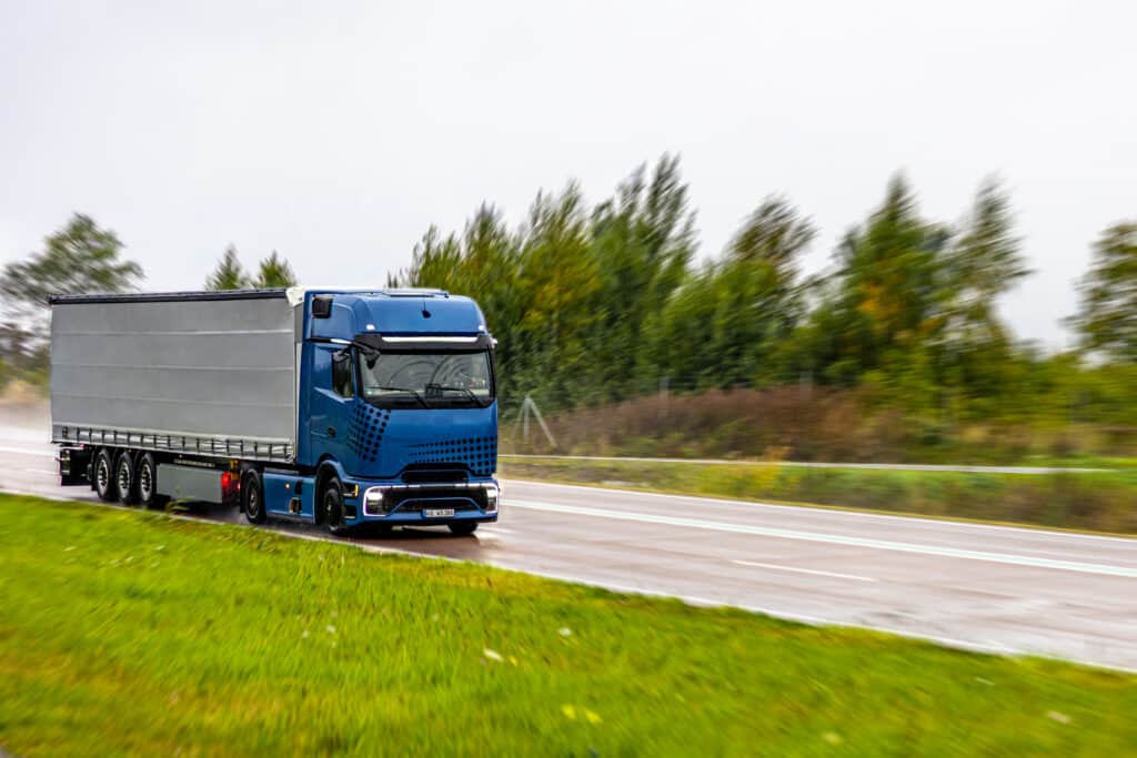 Blue semi truck driving on wet highway